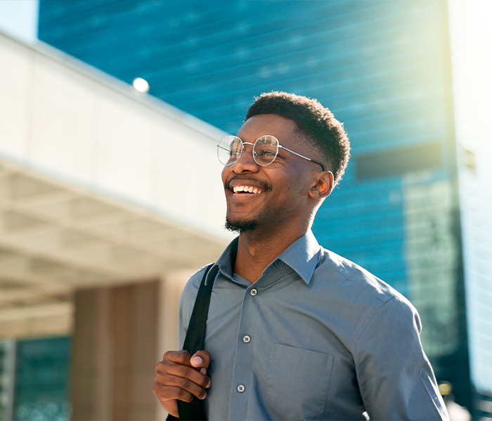Man in glasses smiling and walking down street with knapsack
