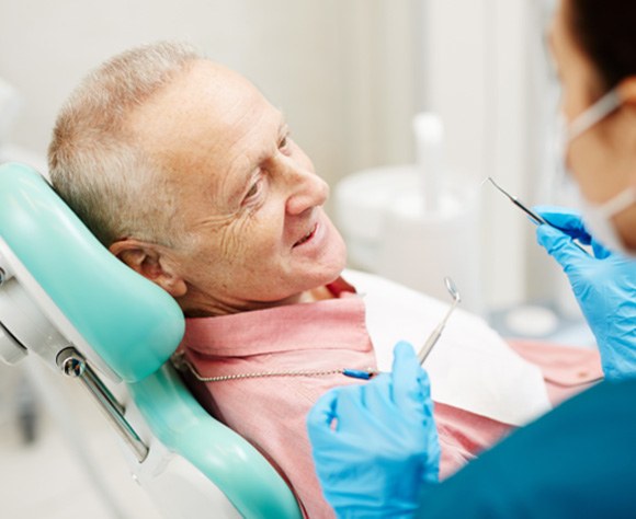 Dentist talking with older male patient about teeth