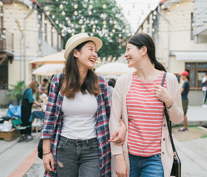 Two women walking down street together smiling