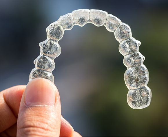 Hand holding a clear aligner