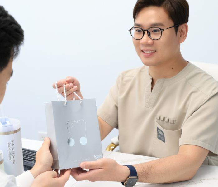 Male team member with glasses handing patient a bag