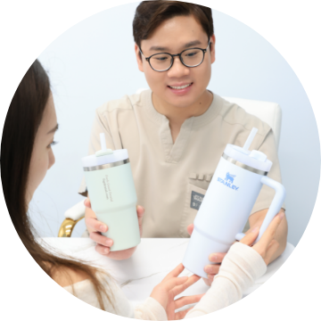 Dentist with glasses showing mugs to patient