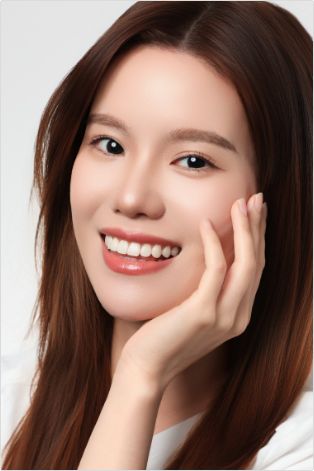 Woman in white shirt smiling and rubbing one cheek