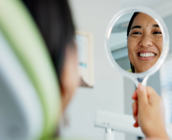 Woman smiling while looking at reflection in mirror